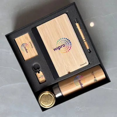 This eco-friendly corporate gift set for Wipro features items made with bamboo accents. The set includes a bamboo notebook, pen, bottle, keychain, and card holder, all branded with the company logo for a sustainable and stylish gift.
