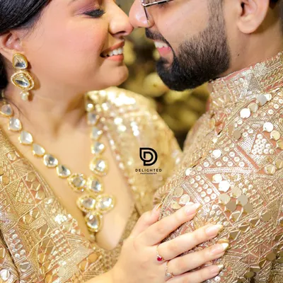 A beautiful close-up from a Roka ceremony, capturing the couple's joyful smiles and the intricate details of their coordinated gold outfits and jewelry.