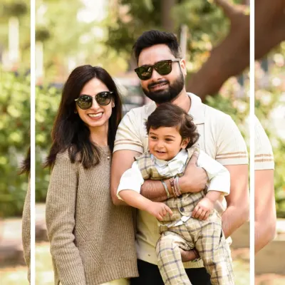 A stylish family of three poses for a portrait during their outdoor session in a park. The natural sunlight and greenery create a warm and vibrant backdrop.