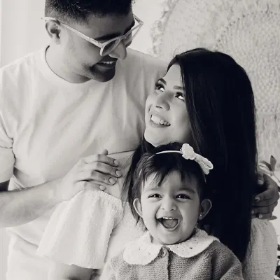 A joyful family portrait in black and white. The baby's wide-mouthed laugh is the center of this happy moment.
