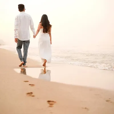 A beautiful, simple moment of a couple walking along the shoreline, leaving footprints in the sand as they start their new journey.