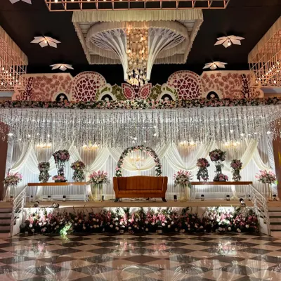 An absolutely breathtaking reception stage. This grand design features a canopy of hanging crystals, massive floral arrangements, and a multi-level stage, creating an atmosphere of pure opulence.