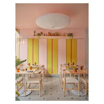 The alfresco dining area at Lucky Chan combines a playful pink wall with bold yellow and red tile panels. The design uses color and pattern to create a cheerful and highly photogenic restaurant interior.