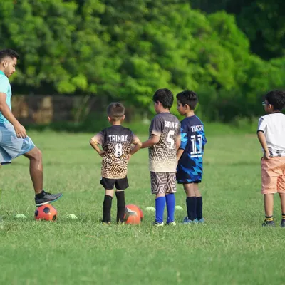 A coach demonstrating a skill to a group of attentive young players. This image captures our hands-on approach to coaching and mentorship.