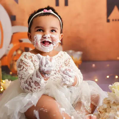 Capturing a moment of pure delight during a cake smash, with a happy, frosting-covered smile that says it all.