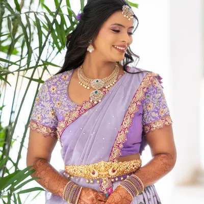 A smiling bride in her custom lilac langa dhavani, featuring a beautifully embroidered blouse and delicate detailing.