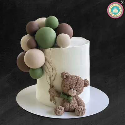 A charming teddy bear cake with a modern, earthy feel. This design features a sweet, textured teddy bear holding a bundle of green, brown, and cream-colored balloons against a clean white cake.
