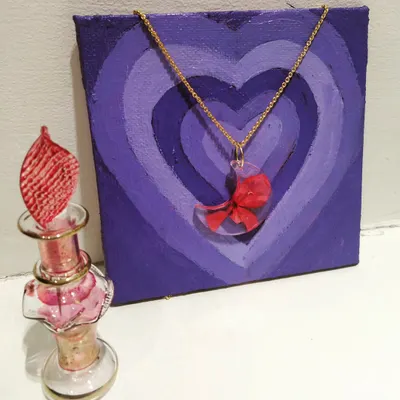 This crescent moon resin pendant holds a tiny, preserved red flower, hung on a delicate gold chain. It's a unique piece of wearable floral art.
