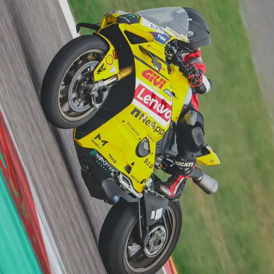 Power on display. A rider lifts the front wheel of a yellow Ducati Panigale, showing incredible control and confidence on the main straight at Buddh International Circuit.