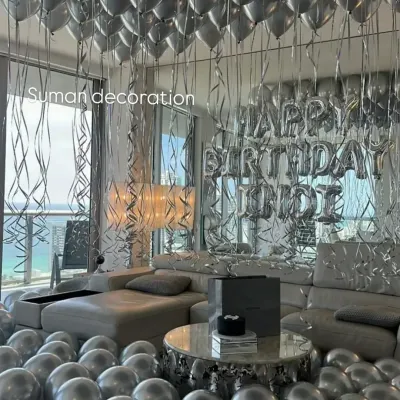 A full room transformation for a birthday surprise. The space is filled with silver helium balloons on the ceiling and floor, with a "Happy Birthday" foil balloon banner as the centerpiece.