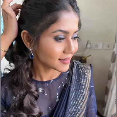 A modern party look featuring blue smokey eyes and a messy ponytail for Anuja. This is perfect for a cocktail party or reception.
