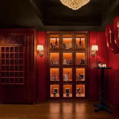 The "Vault" is the first room guests enter from a service elevator. This dramatic, all-red space features vintage chandeliers and private liquor lockers, immediately setting a secretive and exclusive tone for the speakeasy experience.