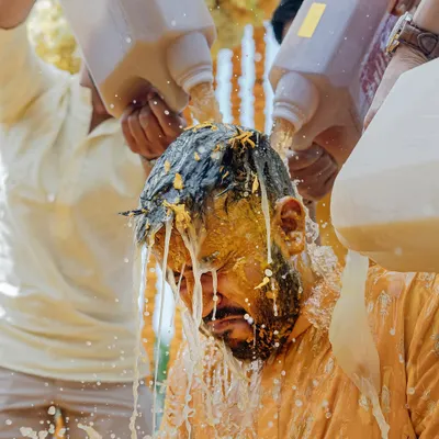 The Haldi ceremony gets wild as the groom is doused with milk and turmeric by his friends at this fun-filled beach wedding in Thailand.