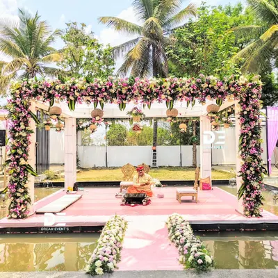 A full view of the stunning water mandap, showcasing the lush floral canopy and the aisle lined with flowers. This design integrates the natural beauty of the venue with bespoke decor for a truly magical wedding ceremony.