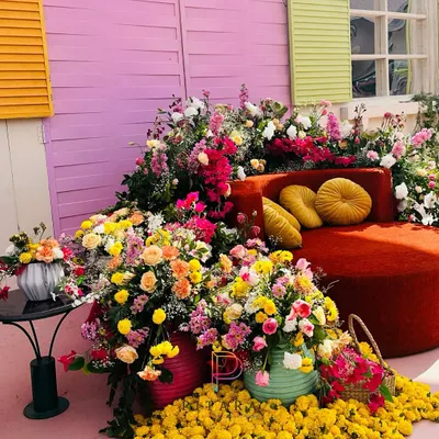 A Haldi that’s a riot of color. This seating area is surrounded by an explosion of marigolds, roses, and bougainvillea against a backdrop of colorful shutters, creating a joyful and picturesque setting.