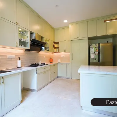 This spacious kitchen is bathed in a soft, pastel green, creating a calm and refreshing atmosphere. The shaker-style cabinets provide a timeless look, while the large island and seamless storage, including a hidden refrigerator, make it incredibly functional.