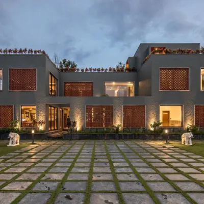 The main facade of The Grey Grotto at twilight. The home's architecture is defined by its clean lines, textured grey paint, and warm interior lighting that creates an inviting glow.