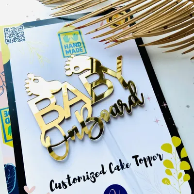 The "Baby on Board" topper for baby showers, shown here in its custom packaging, making it a perfect gift for expecting parents.