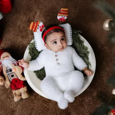 A festive newborn portrait for my son's first Christmas. We used classic holiday props like a Santa figure, candles, and a Christmas tree to create a warm and magical atmosphere for his baby photoshoot.
