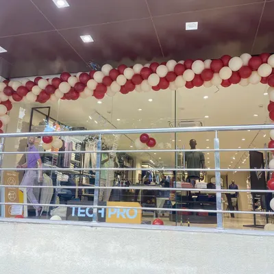 A classic spiral balloon arch in red and white for the grand opening of a 'Tech Pro' retail store. This type of decoration is effective for attracting attention and creating a festive launch day atmosphere.