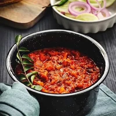 A bowl of my Yummy Fire Roasted Addictive Tomato Chutney, garnished with a fresh curry leaf. The fire-roasting process gives it a deep, smoky flavour.
