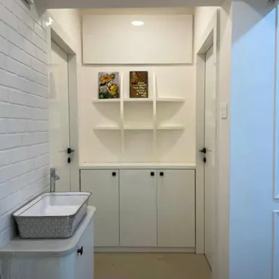 A complete entryway makeover. We transformed this passage by adding a full wall of concealed storage, open display shelves, and a stylish washbasin area, making it incredibly functional without feeling cluttered.