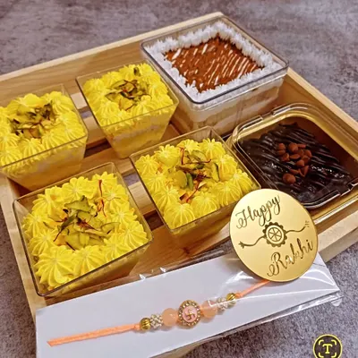 My Rakhi hampers are a complete gifting solution, combining delicious desserts with festive essentials. This hamper features a selection of my best-selling eggless dessert tubs, a rakhi, and a personalized acrylic tag, all presented in a beautiful tray.