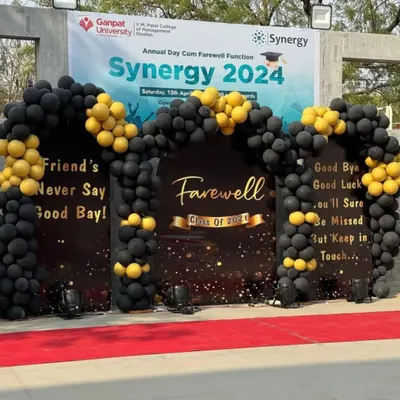 We create impressive setups for major institutional events like this college farewell function. This decor features a large, fully branded backdrop for "Synergy 2024," a dramatic black and gold balloon arch, and a red carpet entrance to provide a premium experience for attendees.