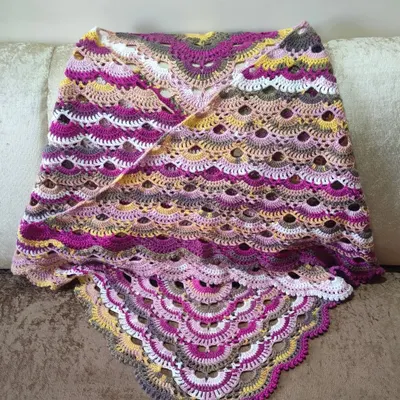 The finished Virus Shawl, draped to show its gorgeous, scalloped pattern. The self-striping yarn does all the colorwork for you, creating beautiful transitions from pinks and purples to yellows and greys.