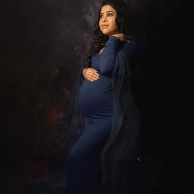 A portrait that feels like a painting. The deep blue gown and artistic lighting create a moody and powerfully elegant maternity photograph.