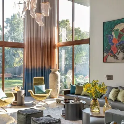 Sunlight floods this spacious living room through floor-to-ceiling windows, highlighting the vibrant artwork and designer furniture. We focused on creating a connection with the outdoors, making the room feel airy and expansive.