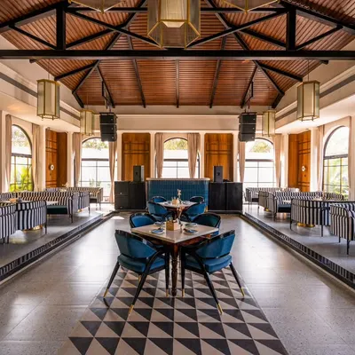 This perfectly symmetrical wide shot of Vamos Experience is designed to showcase the grandeur and meticulous design of the main dining hall. The leading lines in the flooring guide the eye, emphasizing the scale and elegance of the venue.