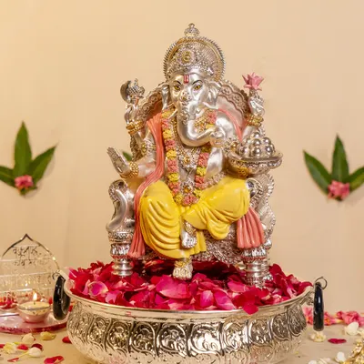 I designed this magnificent silver-plated Ganesha to be a centerpiece of devotion. Seated in a large urli bowl filled with fresh rose petals, this idol captures the grandeur and grace of the deity, perfect for welcoming blessings into your home.