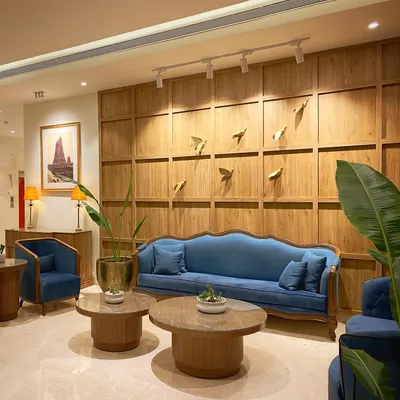 The completed entrance lobby at Keys Select Kattima, Chennai. The combination of classic blue sofas, warm wood paneling, and subtle metallic bird art creates a sophisticated yet comfortable waiting area for guests.