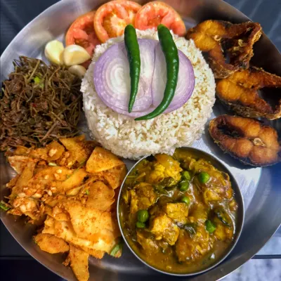 A classic non-veg thali with fried fish, fish curry with peas, and a side of Kangsu, a healthy stew made with pennywort and bamboo shoots.