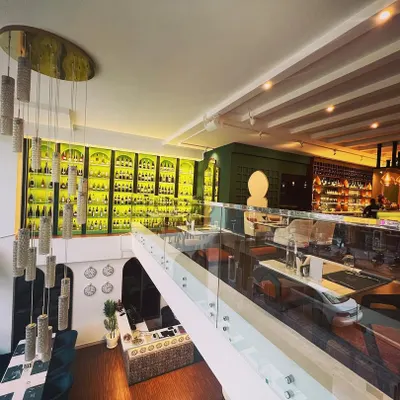 An elevated view of our dining space, showcasing the grand, backlit wine cellar and the seamless flow between the bar and dining areas. The design reflects our commitment to a luxurious yet comfortable experience.