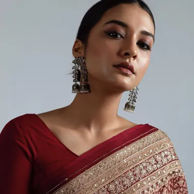 A powerful, royal inspired look from a professional photoshoot. It features dramatic smokey eyes, a flawless matte base, and a sleek low bun to create a regal and striking image.