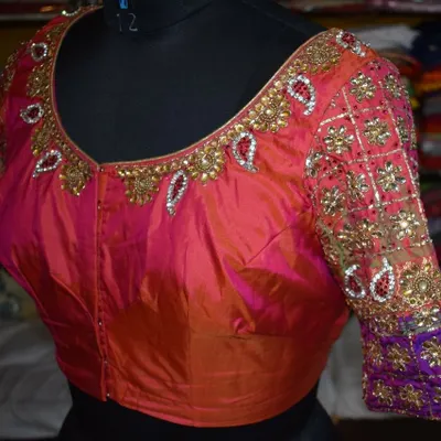 This is the front view of a bridal silk blouse I custom-made. It features heavy Kundan and beadwork on a dual-tone pink and orange fabric, with detailed embroidery covering the sleeves for a truly regal look.