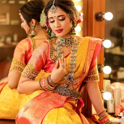 A beautiful moment of the bride at her vanity, surrounded by lights. This shot captures the final touches and the quiet anticipation before the main event, highlighting her stunning jewelry and makeup.