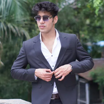 A classic charcoal grey blazer being buttoned up. This is a versatile piece for any man's wardrobe, perfect for a smart casual look.