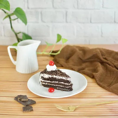 A clean and bright shot of a slice of black forest cake, styled simply for a cafe or bakery menu. This highlights the minimalist food photography style available.