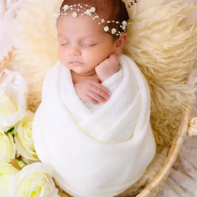 A classic portrait of newborn serenity. We gently swaddle your baby in a soft white wrap, creating a sense of security and peace that allows us to capture their perfect, sleeping form.