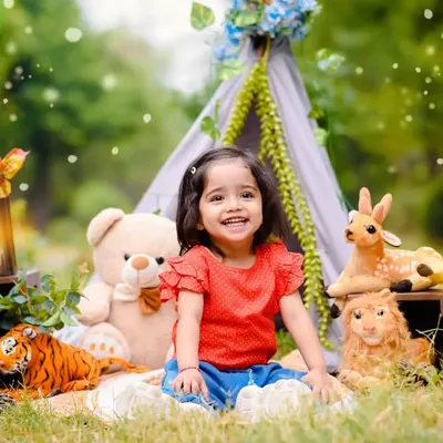Anaya's second birthday shoot was a joyful outdoor picnic. The natural light and greenery create a beautiful setting, and the props make it extra fun.