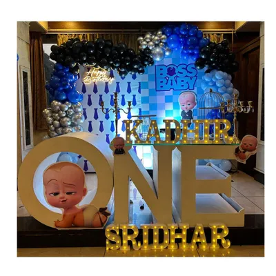 A complete Boss Baby themed first birthday stage. The setup features large "ONE" marquee letters, a custom backdrop with the movie's motifs, and a striking balloon arrangement in blue, black, and silver.