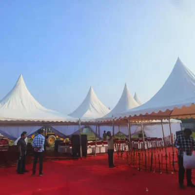 A corporate event setup in progress in Greater Noida, featuring multiple white pagoda tents arranged on a red carpeted area. This structure is ideal for creating separate zones for stalls, registration, or activities.