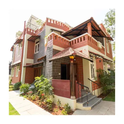 The inviting entrance of the award-winning GRIHA Platinum rated home, featuring a mix of stone and brick, with a traditional tiled porch roof.