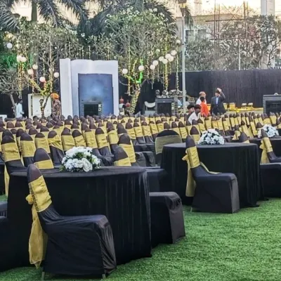 This outdoor venue features a mixed seating arrangement to serve different purposes. It includes banquet-style round tables for dining and rows of theater-style seating for a presentation or performance, all coordinated with a black and gold theme.