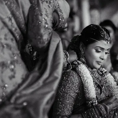 A close-up, black and white shot capturing the solemn moment of the mangalyam ceremony. This perspective emphasizes the significance of the ritual and the bride's serene expression.