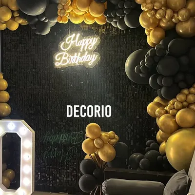 A surprise 50th birthday setup at home, featuring a bold black and gold theme. The decor includes a black sequin wall, a 'Happy Birthday' neon sign, and large '50' marquee numbers, transforming the living room into a stylish party space.