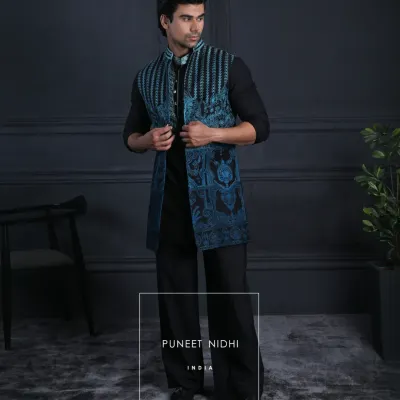 A tailored black Achkan paired with a teal embroidered jacket. The precise embroidery, bold contrast, and sharp mandarin neckline create a look of sophisticated, contemporary style.